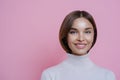 Close up portrait of lovely satisfied joyful woman with dark hair, smiles pleasantly, shows white teeth, wears poloneck, isolated