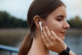 Close up portrait of a lovely young fitness girl listening to music through wireless earphones outdoors. Royalty Free Stock Photo