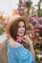 Close up portrait of lovely young romantic woman with flower in hand posing on sunset. Wearing straw hat Royalty Free Stock Photo