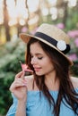 Close up portrait of lovely young romantic woman with flower in hand posing on sunset. Wearing straw hat Royalty Free Stock Photo