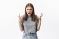 Close up portrait of mad beautiful caucasian student girl with brown hair in casual clothes looking in camera with angry