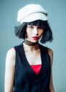 Close-up portrait of magnificent young girl in dark vest and white knitted hat, looking on camera, isolated on blue Royalty Free Stock Photo