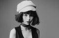 Close-up portrait of magnificent young girl in dark vest and white knitted hat, looking on camera, isolated on blue Royalty Free Stock Photo