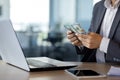 Close-up portrait of male hands counting dollars, man sitting at desk in office using laptop in suit and counting money Royalty Free Stock Photo