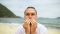 Close-up portrait man apply sun cream protection lotion, looking at camera. Funny man on beach near sea smearing Royalty Free Stock Photo