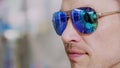 close-up, portrait of man in blue sunglasses at optical store. in spectacles is reflected the showcase of optics and