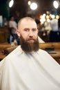 Male client with beard sitting in hairdresser chair. Serious man with long brown beard. Modern popular lumberjack style. Royalty Free Stock Photo