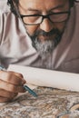 Close up portrait of man busy studying a paper design map on the desk table. Professional worker activity. Mature people working Royalty Free Stock Photo