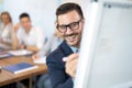 Close up portrait of man in formalwear and eyeglasses using pen, writing graphs and data on flip chart in meeting room. Royalty Free Stock Photo