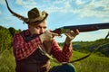 Close up portrait with man, hunter wearing vintage clothes and checked shirt shooting prey with a rifle over marvelous Royalty Free Stock Photo