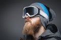 Close-up portrait of a man with a red beard wearing a winter hat, coat and protective snow glasses, looking away Royalty Free Stock Photo