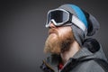 Close-up portrait of a man with a red beard wearing a winter hat, coat and protective snow glasses, looking away Royalty Free Stock Photo