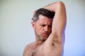 Close up portrait of man, smelling his armpit, feeling bad odor, wants to take a shower, needs antiperspirants