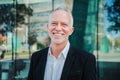 Close up portrait of mature adult business man with gray hair and suit smiling and looking at camera with succesful