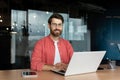 Close-up portrait of mature businessman inside office, man with beard and red shirt smiling and looking at camera Royalty Free Stock Photo