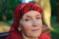 Close up portrait of mature woman dressed in red clothes and sitting on the bench and enjoying a good weather and sunset Royalty Free Stock Photo