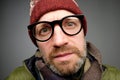 Close up portrait of middle aged europeam man in funny warm hat and glasses noticing hidden camera.