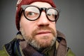 Close up portrait of middle aged europeam man in funny warm hat and glasses noticing hidden camera. Royalty Free Stock Photo