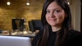 Close-up portrait of middle-aged overweight businesswoman in front of laptop and smiling into camera on office