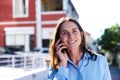 Close up middle aged woman smiling and talking on mobile phone outdoors Royalty Free Stock Photo