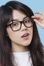 Close-up portrait of mixed race young woman wearing eyeglasses over blue background