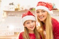 Close-up portrait of mom and daughter in the kitchen wearing Christmas hats Royalty Free Stock Photo