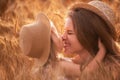 Close-up portrait of mother and daughter in straw hat in wheat field. Little girl kisses young woman Royalty Free Stock Photo