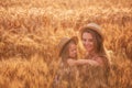 Close-up portrait of mother and daughter in straw hats in slice of wheat field. Girls have fun laugh