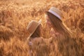 Close-up portrait of mother and daughter in straw hats in slice of wheat field. Girls have fun laugh