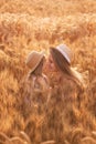 Close-up portrait of mother and daughter in straw hat in wheat field. Little girl kisses young woman Royalty Free Stock Photo