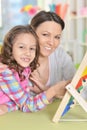 Portrait of mother with little daughter counting with abacus