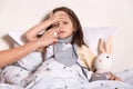 Close up portrait of mother treating her child`s runny nose with nasal spray, little female kid suffers from flu, daughter cathin