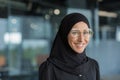 Close-up portrait of Muslim businesswoman in hijab smiling and looking at camera, female worker in glasses working Royalty Free Stock Photo