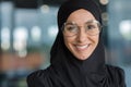 Close-up portrait of Muslim businesswoman in hijab smiling and looking at camera, female worker in glasses working Royalty Free Stock Photo