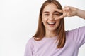 Close up portrait of natural young woman, candid smile of girl showing peace v-sign near eye, concept of woman beauty Royalty Free Stock Photo