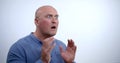 Close-up portrait of a nervous bald middle-aged man in a blue shirt, he sits in the Studio on a white background