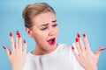 Close-up portrait of nervous unhappy young blonde woman looking at a broken fingernail and crying . red long nails