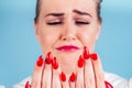 Close-up portrait of nervous unhappy young blonde woman looking at a broken fingernail and crying . red long nails Royalty Free Stock Photo