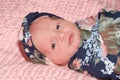 Portrait of a newborn baby girl swaddled laying on pink blanket