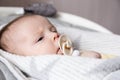 A close-up portrait of a newborn baby girl, who lies in a cradle and sucks a pacifier Royalty Free Stock Photo