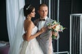Close-up portrait of newlyweds on wedding day. The bride hugs with the groom before the kiss. Man in business suit and