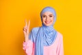 Close-up portrait of nice attractive cheerful muslimah lady showing v-sign isolated over bright yellow color background Royalty Free Stock Photo