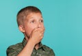 Close-up portrait of a blonde teenage boy in a green shirt with palm print posing against a blue studio background Royalty Free Stock Photo