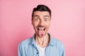Close-up portrait of nice cheerful crazy humorous guy showing tongue out isolated over pink pastel color background