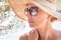 Close up portrait of no makeup natural beautiful woman wearing straw sun hat and sun glasses on the beach in shade of a Royalty Free Stock Photo