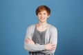 Close up portrait o young attractive cheerful red-haired male student in casual grey outfit smiling with teeth, crossing Royalty Free Stock Photo