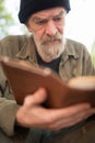 Close up portrait of old beardy man holding book in hands.