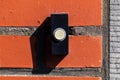 A close up portrait of an old black doorbell with a white button on a red brick wall, ready to be pressed to ring the bell and Royalty Free Stock Photo