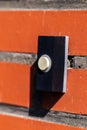 A close up portrait of an old black doorbell with a white button on a red brick wall, ready to be pressed to ring the bell and Royalty Free Stock Photo