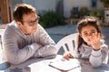Close up portrait of old teacher supervising little kid doing homework outdoors. Beautiful girl doing homework with the Royalty Free Stock Photo